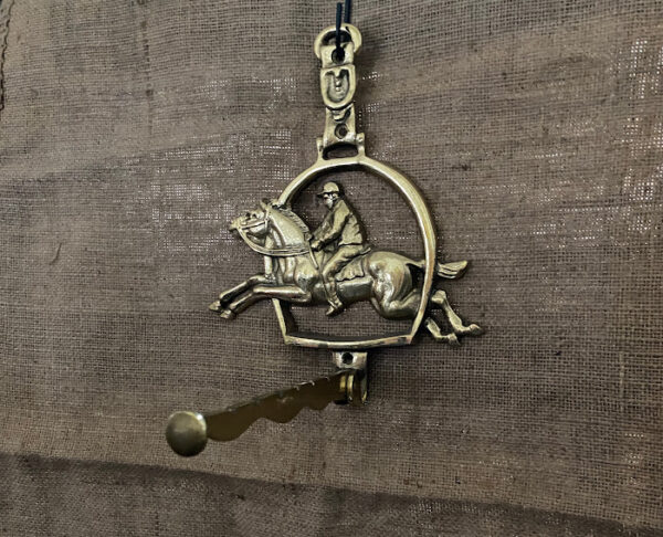 Messing hanger in de vorm van een hoefijzer met paard erin waaronder een inklapbare stang waarop items gehangen kunnen worden